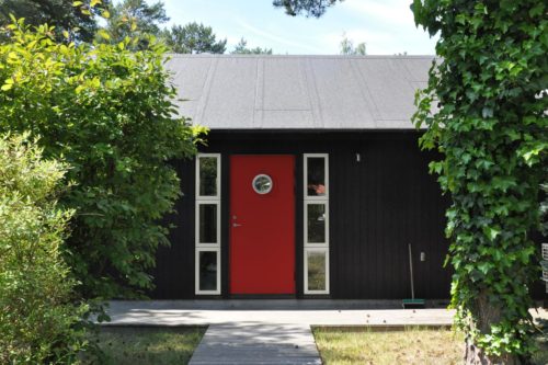 svart trähus med röd dörr